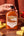 Hand holding a bottle of Sunnybank mild smoky pineapple and habanero hot sauce beside pineapple slices and peppers.
