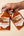 Two bottles of Sunnybank smoky pineapple and habanero hot sauce held against a beige background.