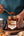 Spoonful of Sunnybank chilli crisp oil held above the jar beside pizza and dumplings.