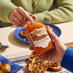 Sunnybank pineapple and habanero hot sauce held over a dining table with savoury toast.